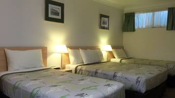 Habitación de hotel con dos camas, cada una con cubrecama floral, lámparas de noche y cuadros en la pared.