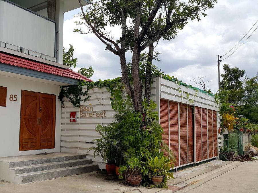 Un bâtiment à deux étages, doté d’un toit recouvert de tuiles rouges, d’une porte en bois et d’une enseigne sur laquelle on peut lire « Baan Barefeet ».