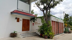Un edificio de dos pisos con techo de tejas rojas, puerta de madera y un letrero que dice "Baan Barefeet".