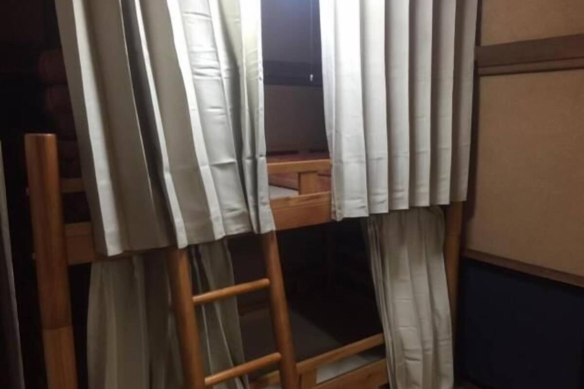 Un lit superposé avec une échelle, des rideaux et une tête de lit en bois.