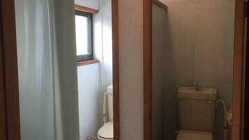 A bathroom with two toilets, a window, and a light fixture on the ceiling.