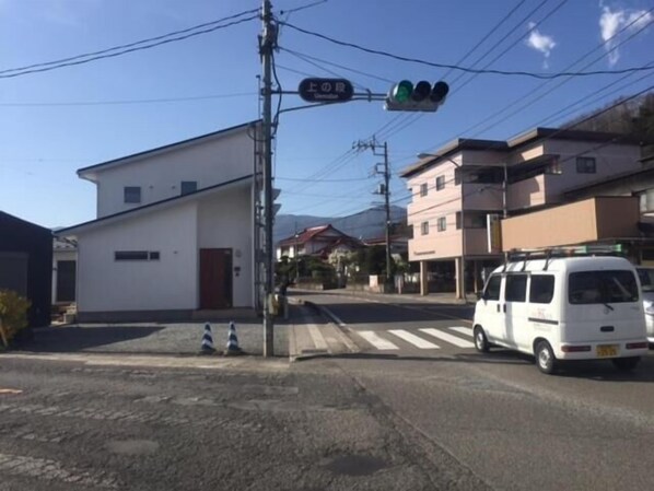 Vista de la calle con un edificio blanco, una camioneta blanca y un semáforo.