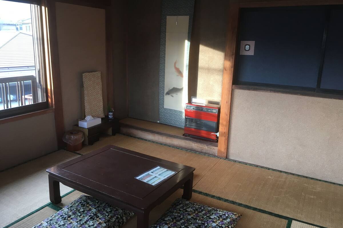 Une pièce de style japonais traditionnel, avec un sol recouvert de tatamis, une petite table en bois et une porte coulissante.