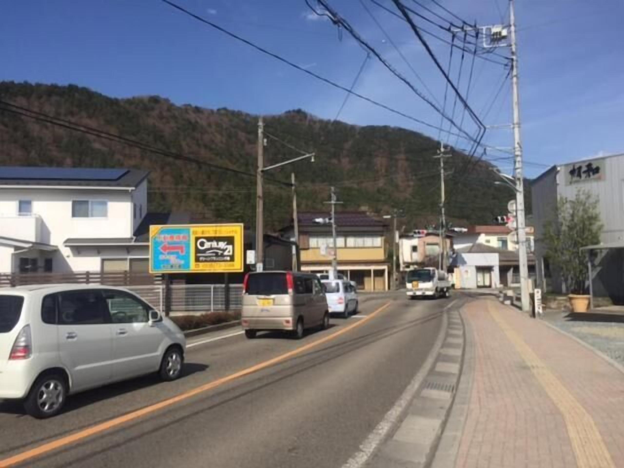 Una carretera con coches, edificios y un cartel.