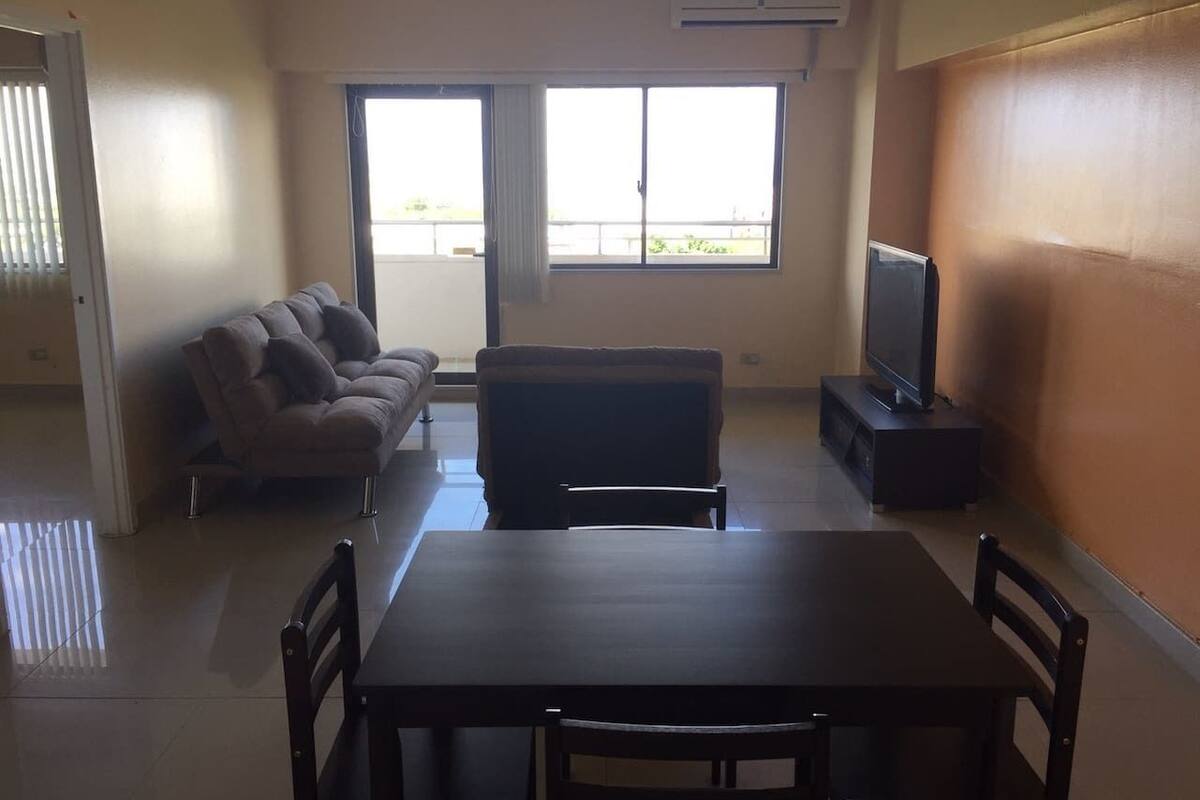 A living room with a sofa, a dining table, and a TV.