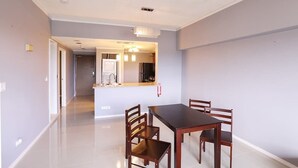 A dining area with a table and chairs, a kitchen in the background, and a hallway leading to another room. - Pia Marine Condominium (Tamuning)