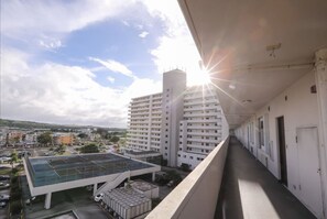 Un largo pasillo con vista a un estacionamiento y edificios al fondo.