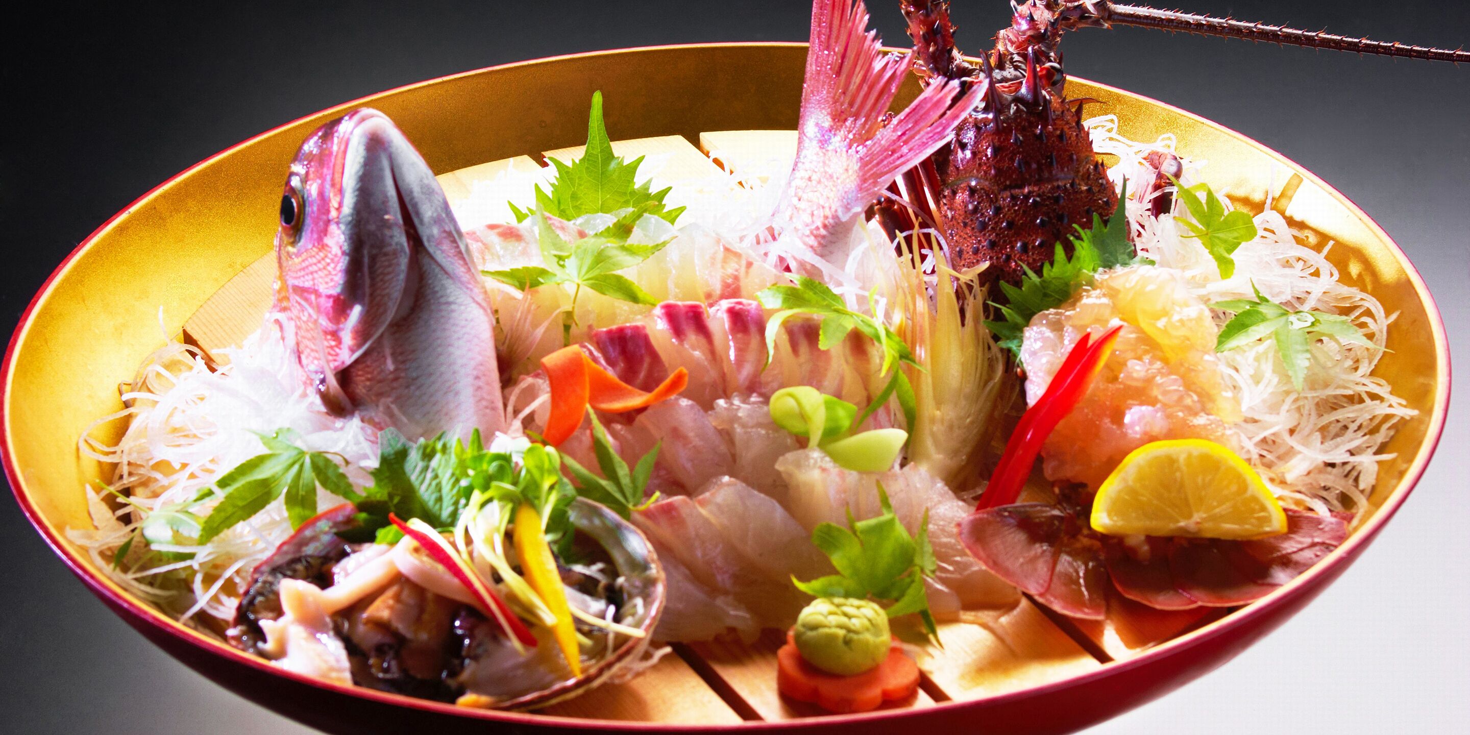 A bowl of assorted seafood including fish, shrimp, and other delicacies, garnished with herbs and vegetables.
