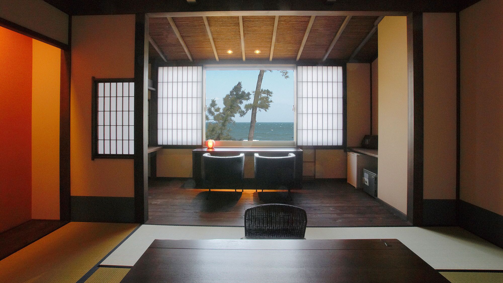 Una habitación tradicional japonesa con suelo de tatami, una mesa baja y vistas al mar.