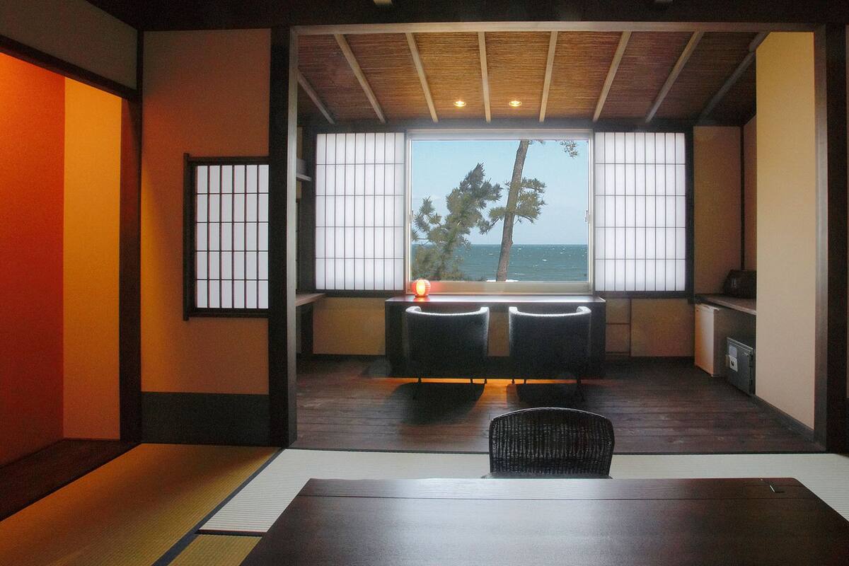 Una habitación tradicional japonesa con suelo de tatami, una mesa baja y vistas al mar.