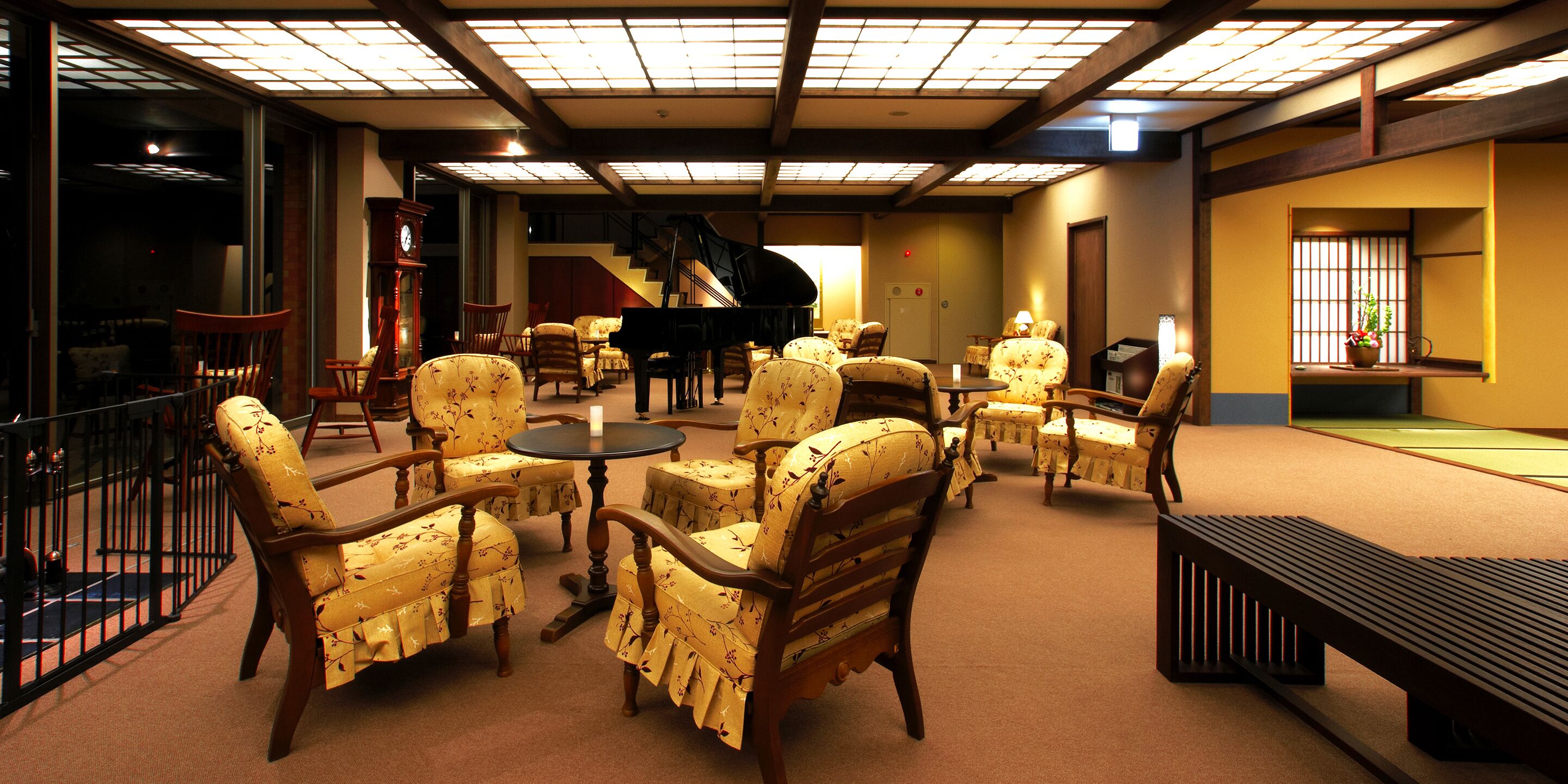 Een ruime zithoek met diverse zitplaatsen, waaronder stoelen en een bankje, rondom een centraal geplaatst piano.