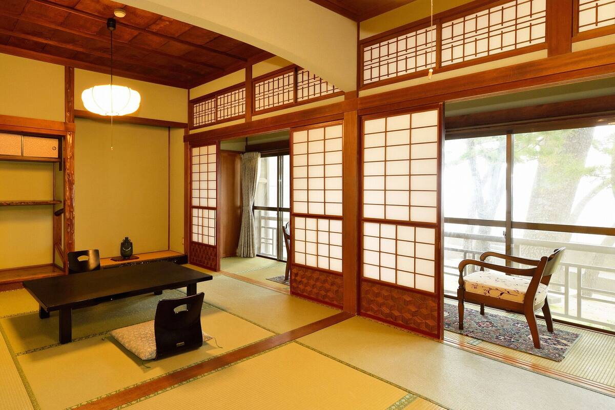 A traditional Japanese room with tatami flooring, a low table, and sliding doors.