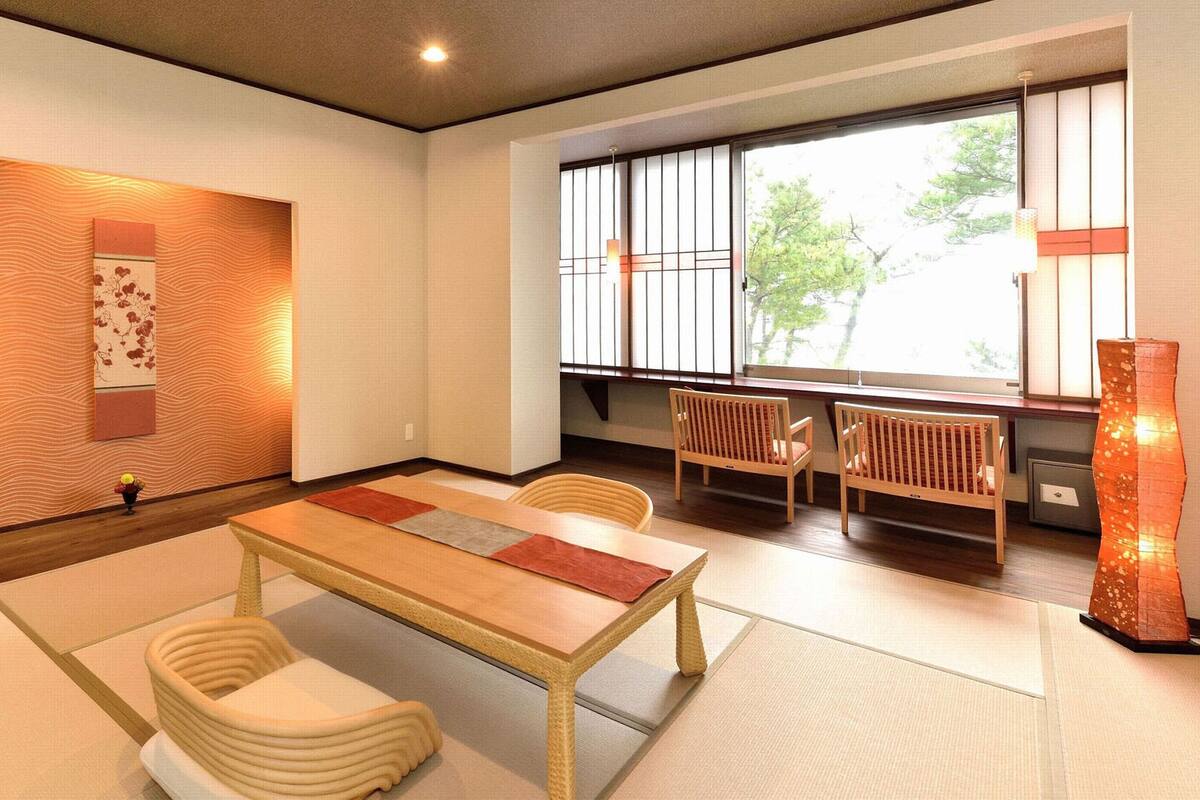 A traditional Japanese-style room with tatami flooring, a low table, and wooden chairs.