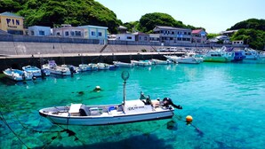 Un puerto deportivo con barcos amarrados, agua turquesa cristalina y edificios al fondo.