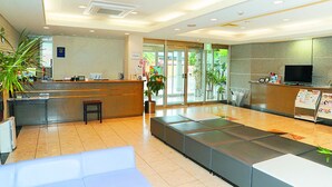 Un área de recepción moderna con mostrador, asientos y televisor.