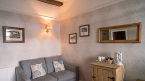 Una habitación con un sofá gris, un aparador de madera y cuadros enmarcados en la pared.