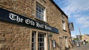 Hotel The Old Hall, con fachada de piedra, ventanas grandes y un cartel que indica que es un Bed & Breakfast.