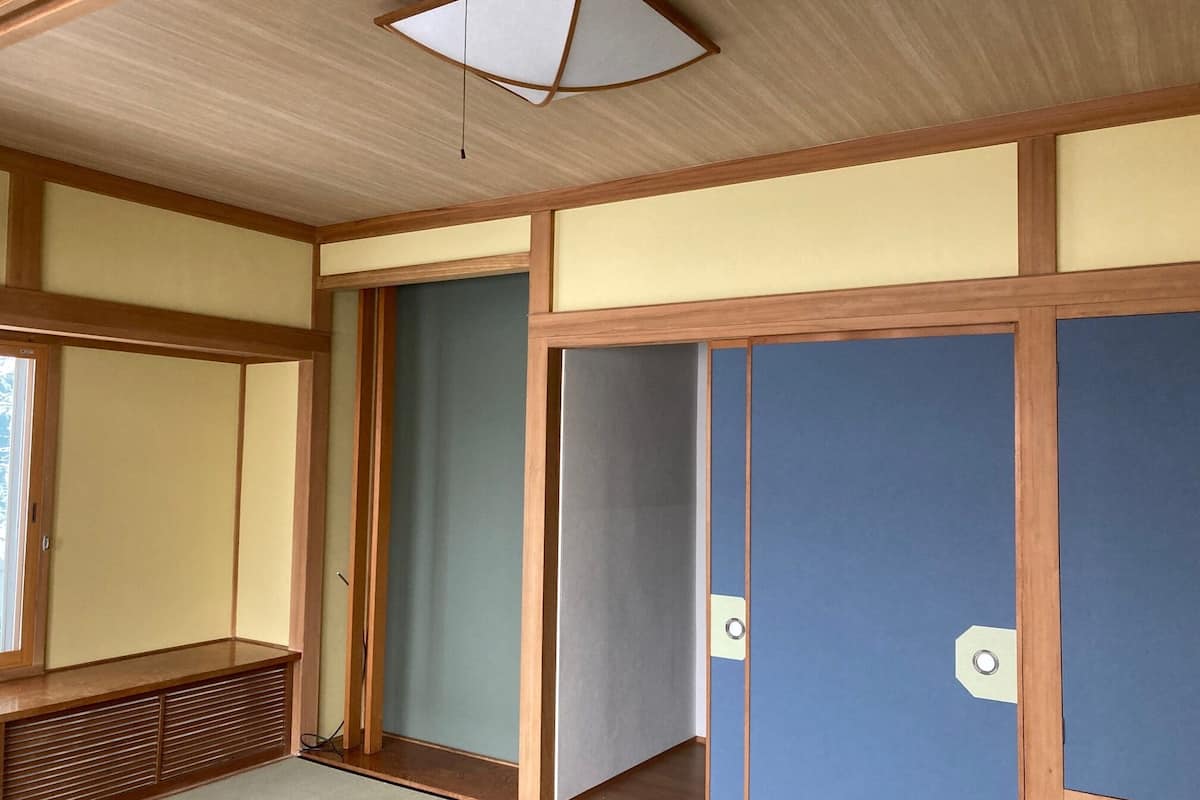 A traditional Japanese room with tatami flooring, sliding doors, and a ceiling fan.