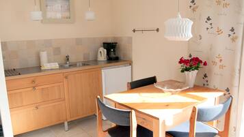 A kitchen with wooden cabinets, a sink, a coffee maker, and a dining table with chairs.