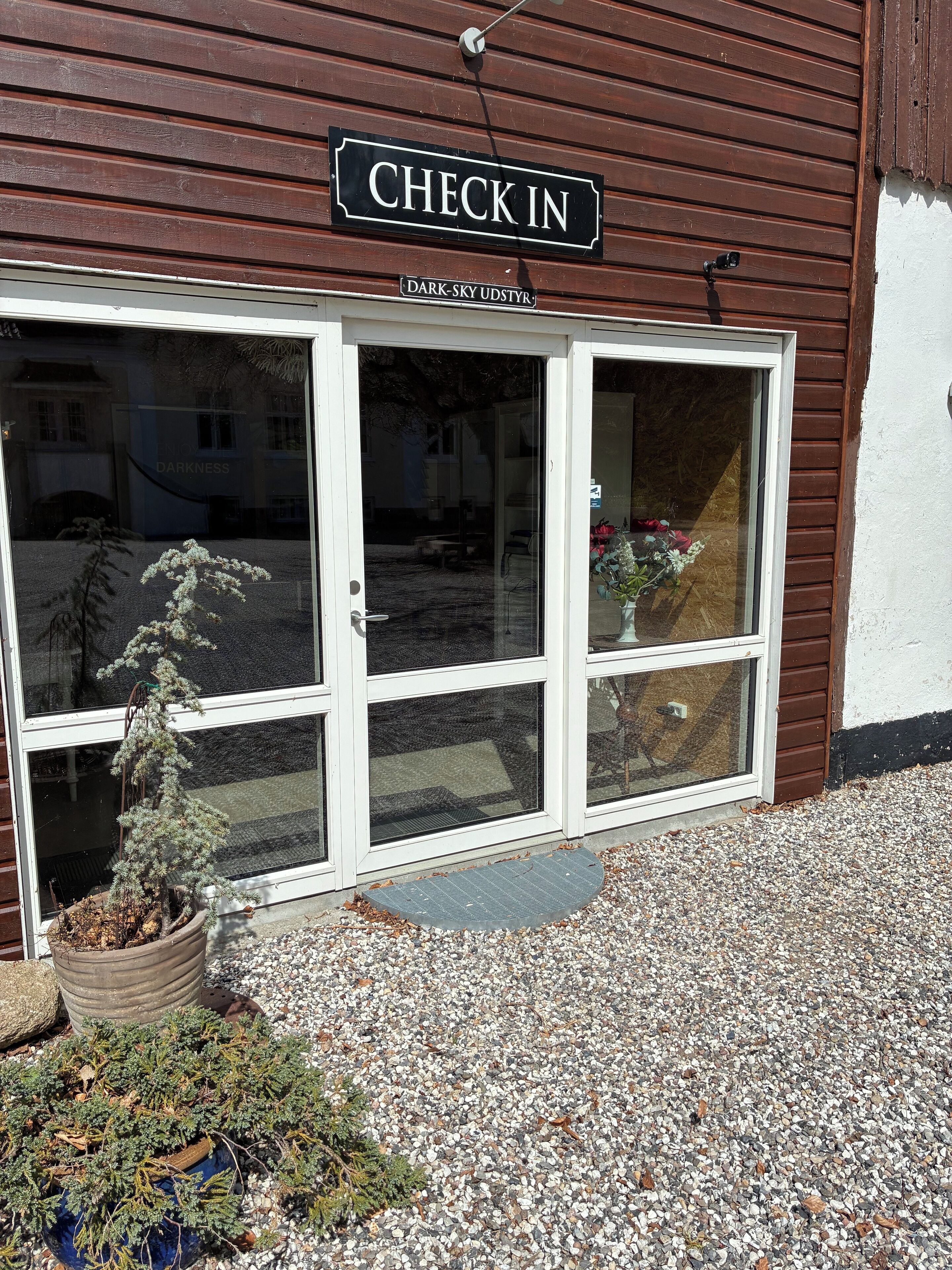 A wooden building with a 'CHECK IN' sign above the entrance.