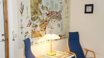 Una habitación con un mapa grande en la pared, dos sillas azules, una mesa de madera y una lámpara.