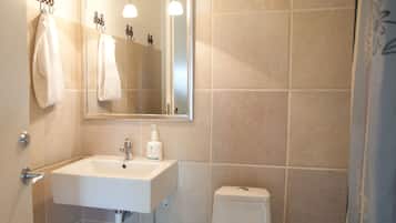 Un baño con lavamanos, espejo, toallero y retrete.