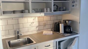 A kitchen with a sink, cabinets, and a coffee machine.