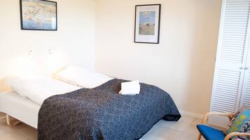Une chambre à coucher avec un lit, une chaise et deux tableaux encadrés accrochés au mur.