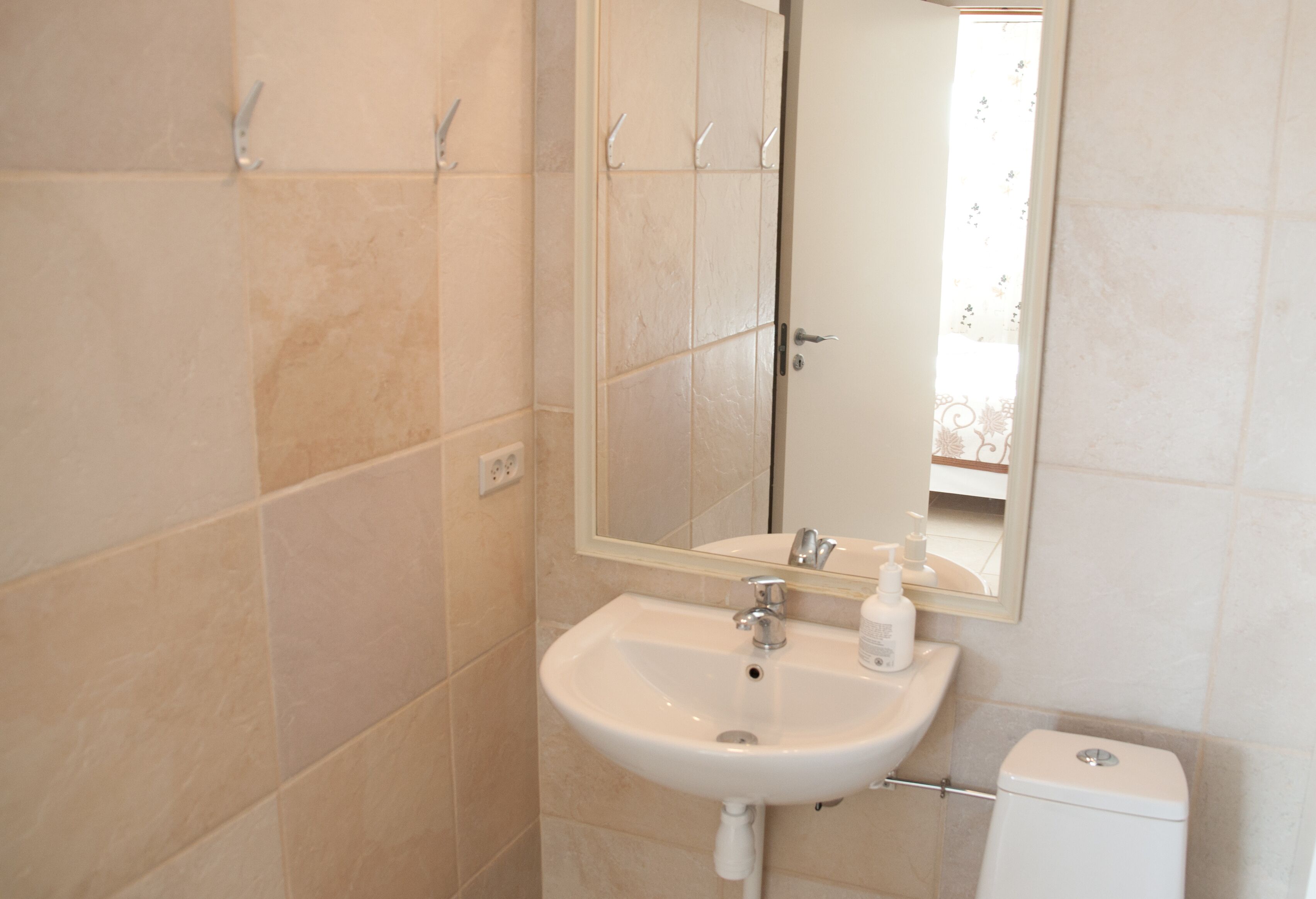 Un baño con un lavabo blanco, un espejo y un inodoro.