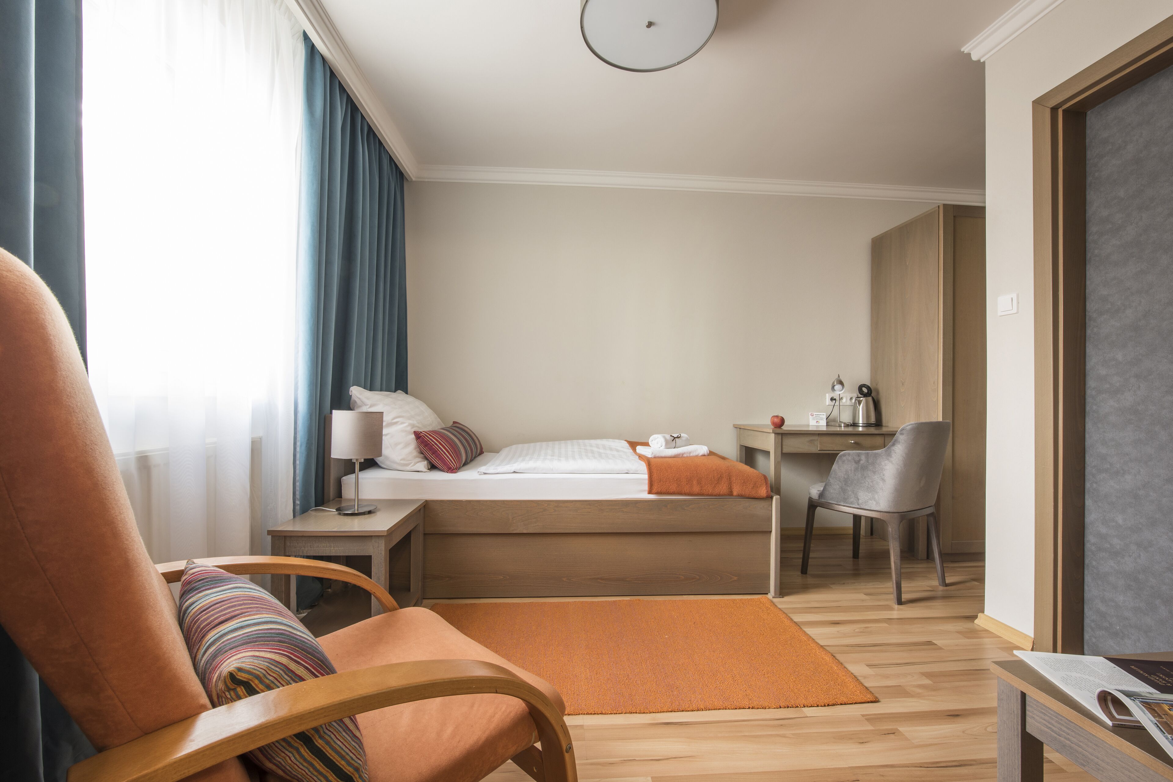 Una habitación de hotel con una cama, un escritorio, una silla y una ventana con cortinas.