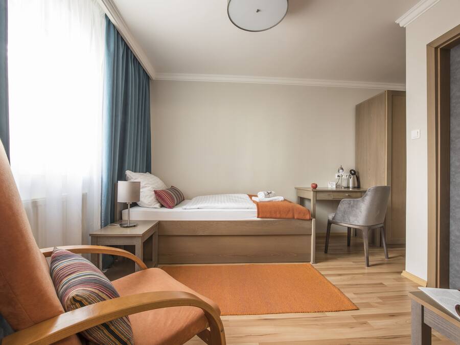 A hotel room with a bed, a desk, a chair, and a window with curtains.