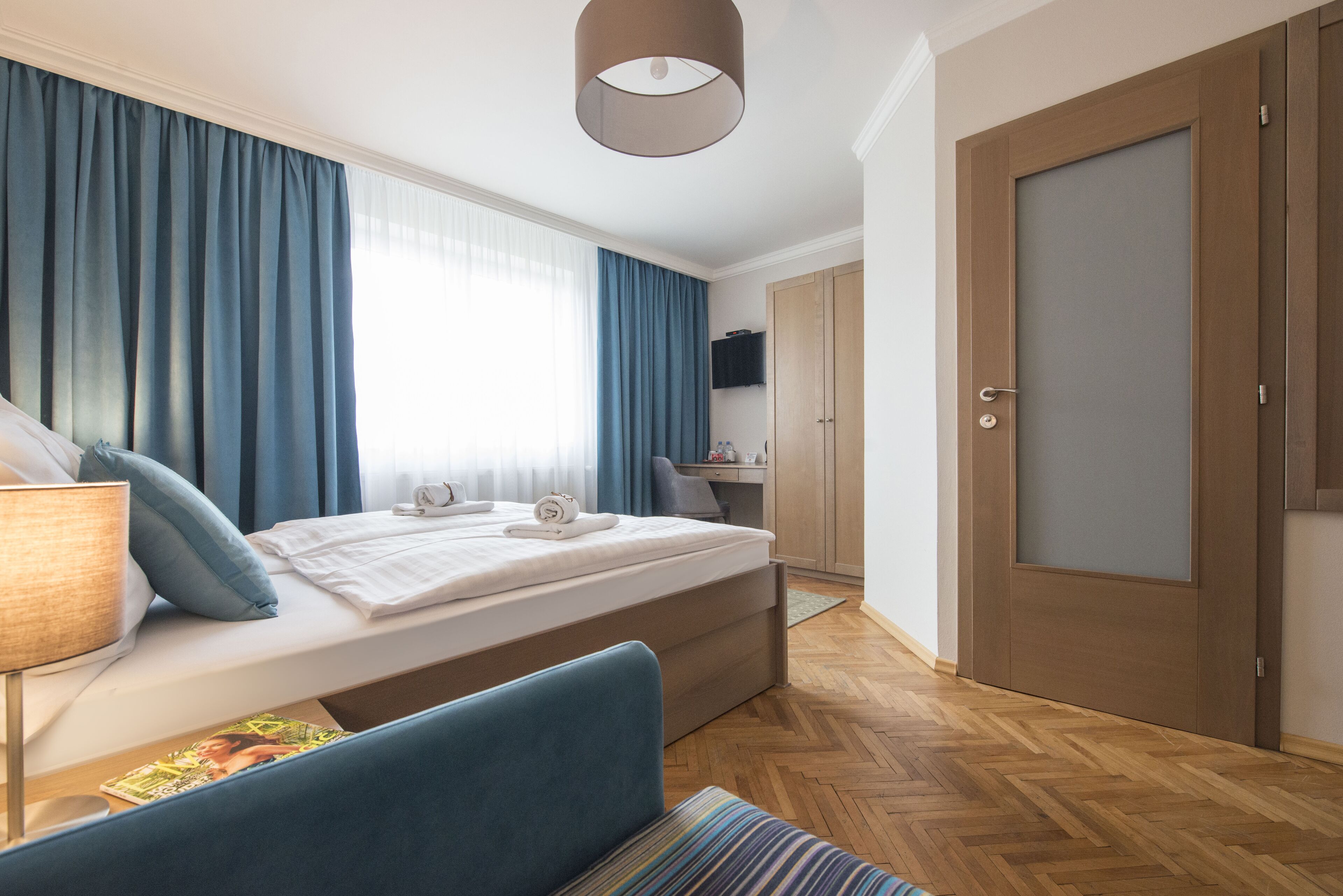 Ein modernes Hotelzimmer mit Bett, Schreibtisch und Kleiderschrank.
