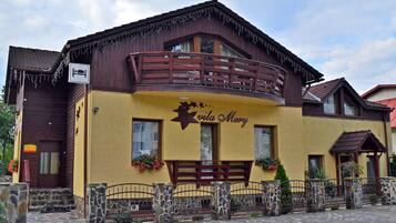 A building with a yellow facade, a wooden balcony, and a sign that reads "Vila Merry".