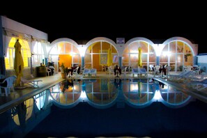 Zona de piscina con sillones de descanso y una piscina reflectante.