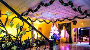 Eine Treppe mit Metallgeländer, verziert mit Weintraubenranken, einem Weihnachtsbaum und Girlanden.