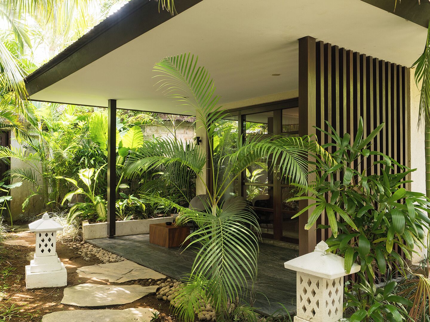 A modern outdoor area with a stone pathway, potted plants, and a wooden deck.