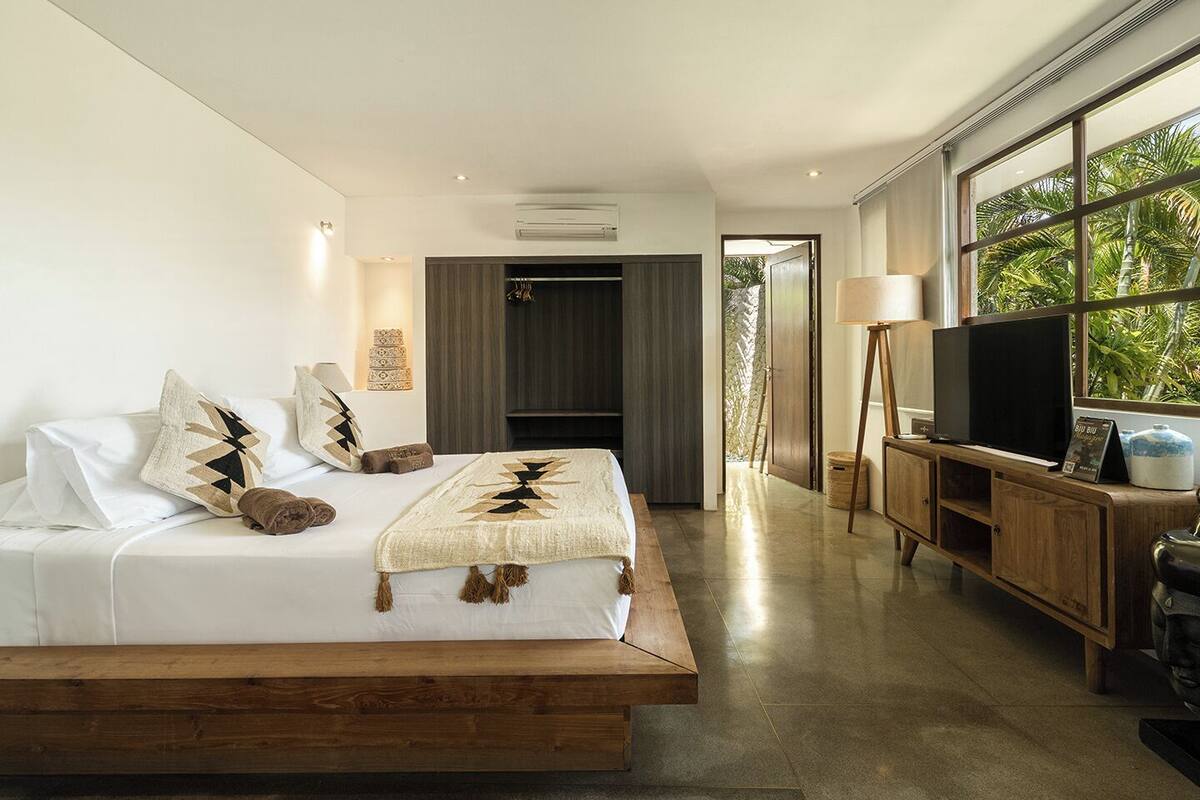 Een moderne slaapkamer met een bed, een televisie en uitzicht op groen.