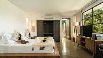 A modern bedroom with a bed, a TV, and a view of greenery.