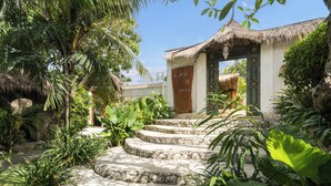 A tropical resort with a thatched-roof building, a stone staircase, and lush greenery. - Biu Biu Resort Bali  (Jimbaran)