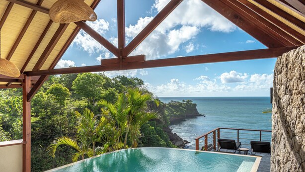 A pool with a view of the ocean and a wooden deck. - Biu Biu Resort Bali  (Jimbaran)