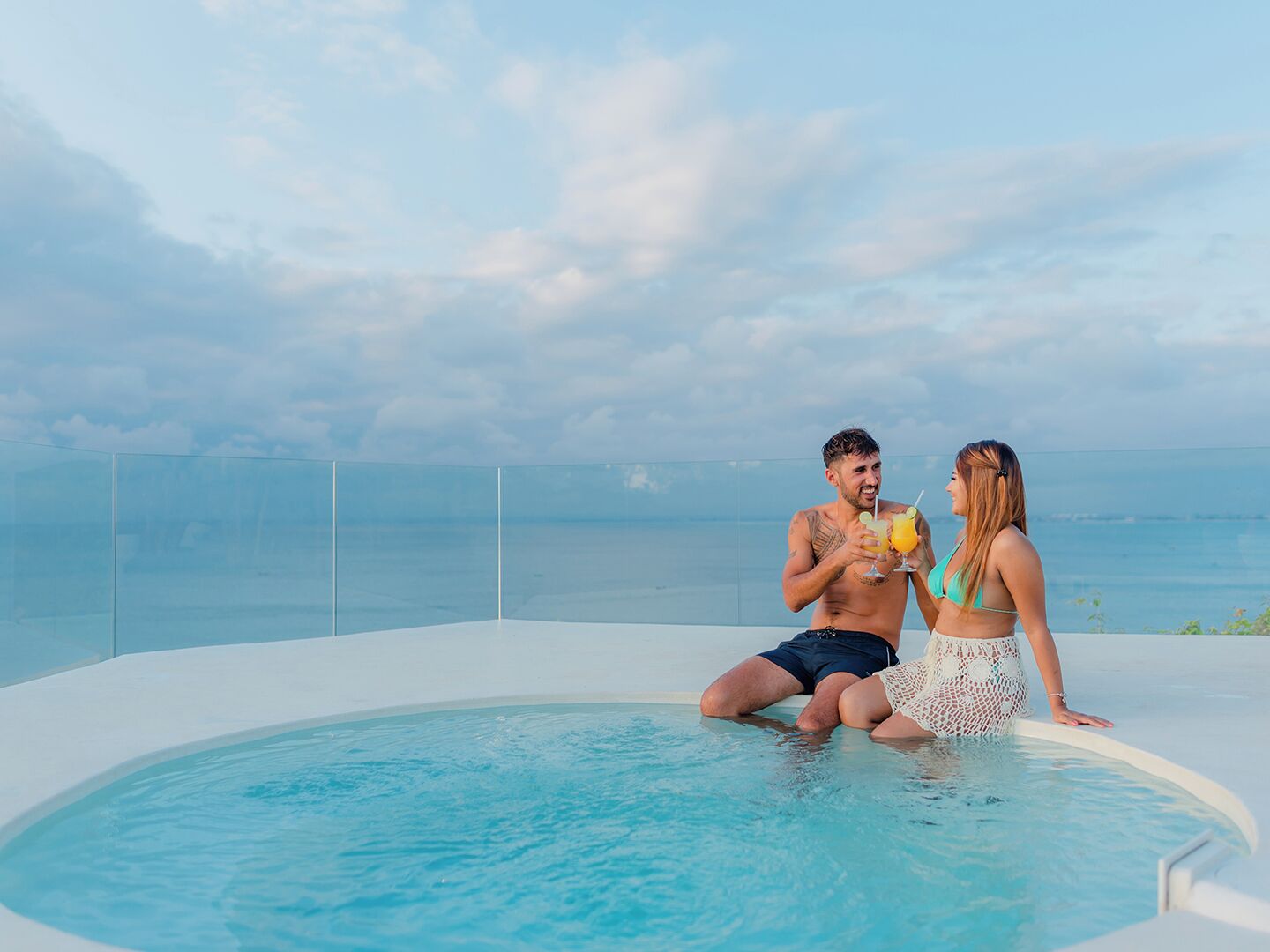 A couple by a pool with a view of the sea.