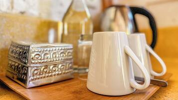 A wooden table with a white mug, a silver box, and a bottle.