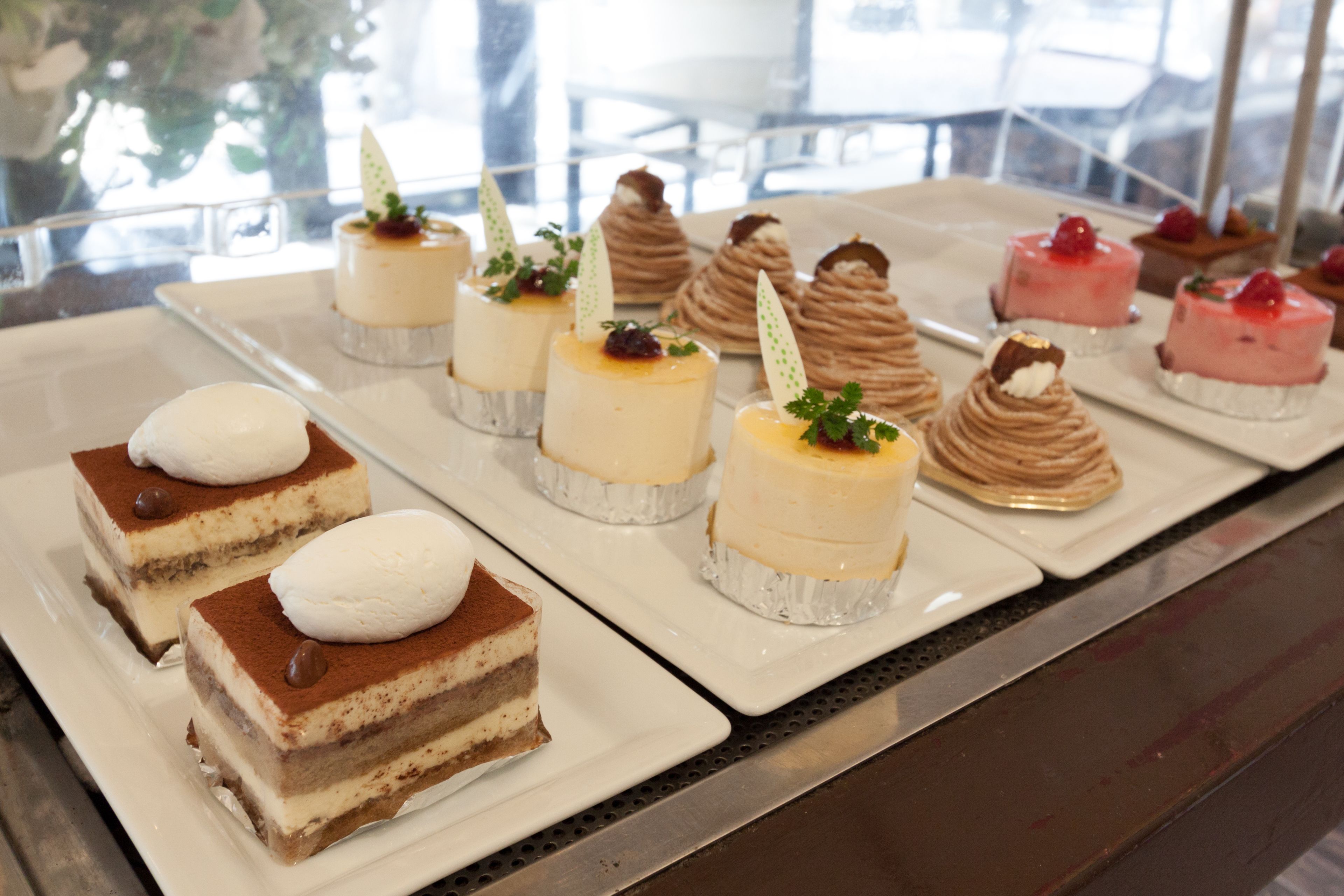 A variety of desserts on a tray, including cakes and pastries, displayed in a restaurant setting.