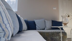 A corner seating area with striped cushions, a stone bench, and a white table with a vase. - Ktima Grammeno (Kantanos-Selino)