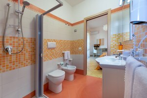 Un baño con ducha, inodoro, bidé y lavamanos.