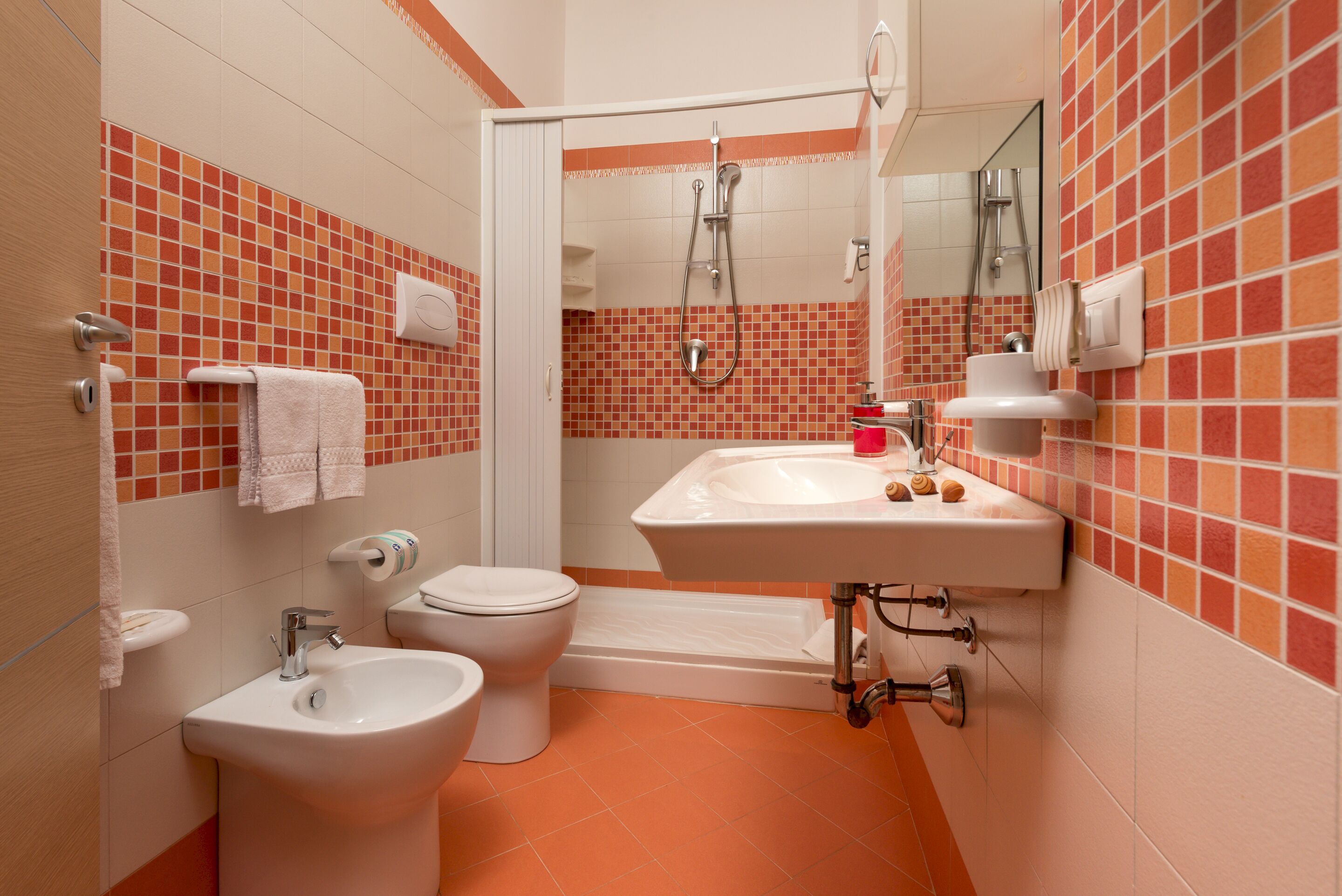 Une salle de bain comprenant des toilettes, un bidet, un lavabo et une douche.