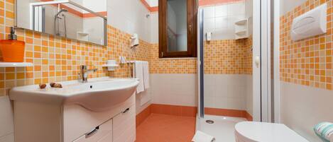 Un baño con un lavabo blanco, una cabina de ducha de vidrio y un inodoro.