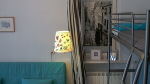 A room with a bunk bed, a teal sofa, a lamp, and a radiator. - Koro de Varsovio - Chmielna 6 (Warsaw)