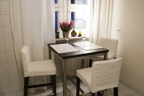 A small dining area with a table and two chairs, a potted plant, a candle, and a clock on the windowsill. - Koro de Varsovio - Chmielna 6 (Warsaw)