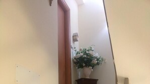 Un escalier en marbre menant à un palier où se trouve un pot de fleurs.